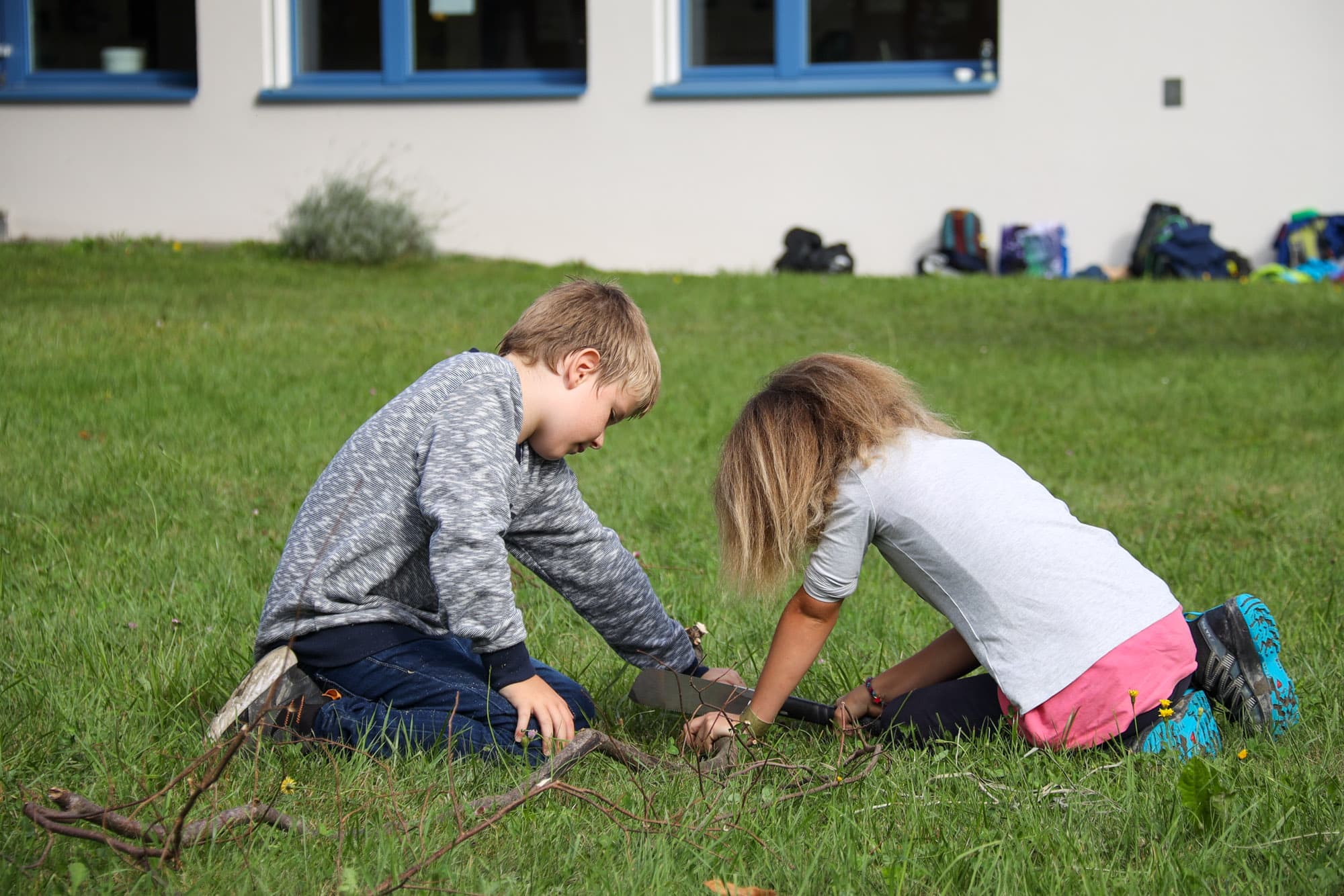 Zwei Kinder sägen zusammen Baumäste.